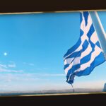 blue-star-ferries-tinos-aktoploikes-grammes-eisitiria 16 | Magic Lamp Blue and white Greek flag waving on a mast against a clear blue sky over the sea horizon