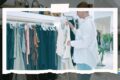 Person in a white shirt browsing dresses on a rack in a bright clothing boutique.