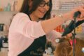 Hairdresser curling a client's hair with a curling iron in a salon, smiles as they work. (informative)