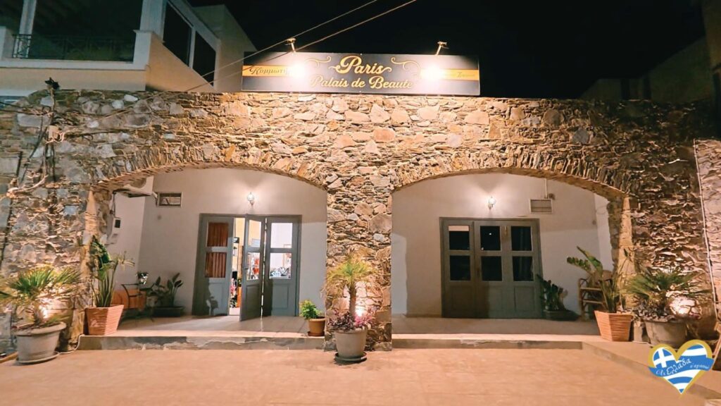 kommotirio-syros-paris-palais-de-beaute 3 | Magic Lamp Night view of a stone building with two arched entrances, warm lights, and potted plants; sign above reads'Paris Palais de Beauté'.