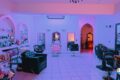 Salon interior with purple lighting, styling chairs, and mirrors along a tiled floor shop-like layout.
