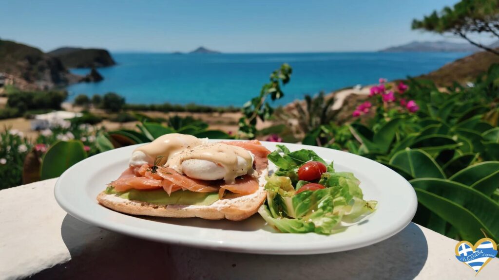 Plate with smoked-salmon Eggs Benedict and side salad on a white table, ocean view in the background.