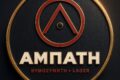 Circular black badge with a gold rim, red geometric emblem, and the bold text 'AMPATH' with 'BYOOZYMTH LAGER' beneath.