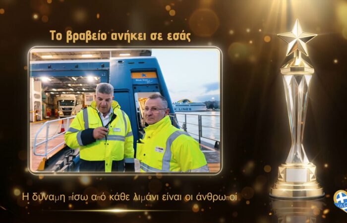 Two port workers in high-visibility jackets stand beside a blue Blue Star ferry at a dock, framed by a glowing panel with a gold trophy to the right.