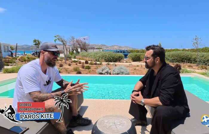 Two men sit and chat beside a bright turquoise pool on a sunny day, outdoor garden setting, with Paros Kite logos in the corner.