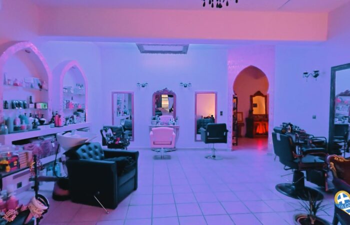 Salon interior with purple lighting, styling chairs, and mirrors along a tiled floor shop-like layout.