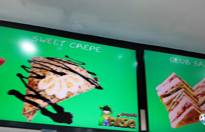 Bright green advertisement featuring a dessert crepe topped with whipped cream and chocolate drizzle; text reads 'SWEET CREPE' on the panel.